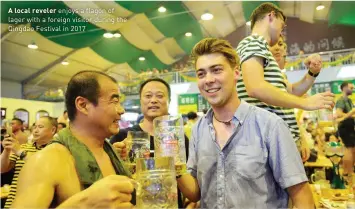  ??  ?? A local reveler enjoys a flagon of lager with a foreign visitor during the Qingdao Festival in 2017