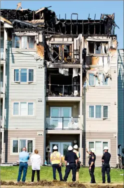  ?? Herald photo by Ian Martens ?? Officials and fire department personnel survey the scene Wednesday morning after fire destroyed part of The Gardens seniors complex Tuesday in the westside neighbourh­ood of West Highlands. @IMartensHe­rald