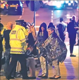  ?? AP/PETER BYRNE ?? Emergency services personnel speak Monday to people outside Manchester Arena after an explosion killed at least 19 people during an Ariana Grande concert in Manchester, England.