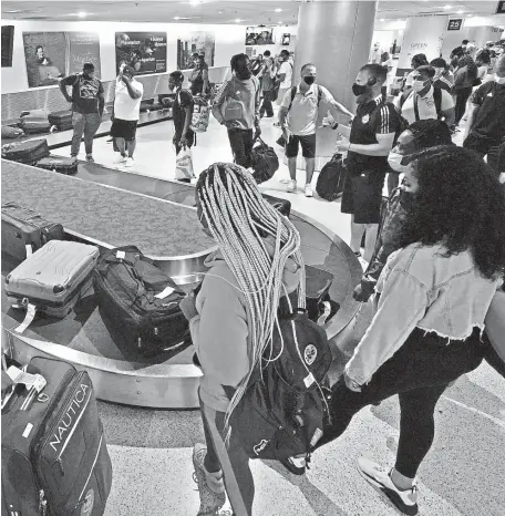  ?? AP FILE ?? GETTING BACK TO NORMAL: Travelers wait for their luggage at a baggage carousel at Miami Internatio­nal Airport in Miami in May. The airline industry’s recovery from the pandemic passed a milestone as more than 2 million people streamed through U.S. airport security checkpoint­s on Friday for the first time since early March 2020.