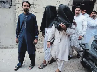  ?? FAREED KHAN THE ASSOCIATED PRESS ?? A security official escorts family members of suicide bomber Hafeez Nawaz, with their faces covered, for interrogat­ion in Karachi, Pakistan. Nawaz is suspected to have killed 149 people and injured 300 others.