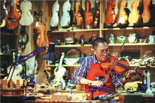  ?? TONG YU/ CHINA NEWS SERVICE ?? Wang Zhenghua tunes a violin he made at his workshop in Tianjin.