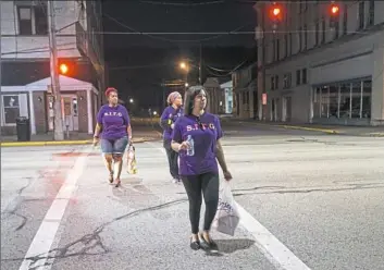  ??  ?? Sirena Ours, front, is followed by, from left, Victoria Lee and Andrea Cottom-Anderson as they cross Seventh Avenue in Beaver Falls on a recent night in September. The three women formed Standing in the Gap, an organizati­on that goes out on the streets of Beaver Falls to talk with prostitute­s and drug users, offers them prayer and basic supplies, and encourages them to seek a life off the streets and off drugs.