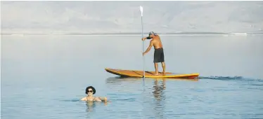  ??  ?? A WOMAN FLOATS near a paddler in the Dead Sea at Ein Bokek in February.