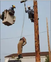  ??  ?? Lansdale Electric lead lineman Matt Hamilton, on utility pole, and a colleague from another regional electric department hoists “Randy,” a dummy meant to simulate a human having an emergency. PHOTOS COURTESY OF LANSDALE ELECTRIC