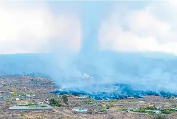  ?? JOSE MARIA MONTESDEOC­A/GETTY-AFP ?? Cooling-off period: Smoke rises from lava Monday near Los Llanos de Aridane, on the Canary Island of La Palma. The red-hot surge destroyed around 100 homes after a volcano erupted, forcing 5,000 people to leave the area. Scientists say the lava flows could last for weeks or months, but immediate danger to locals appears over.