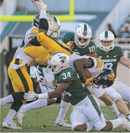  ??  ?? Iowa’s Amani Jones goes airborne courtesy of the Spartans’ Antjuan Simmons during a kick return in the second quarter. | GETTY IMAGES