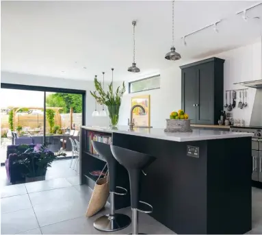  ??  ?? The dark grey kitchen cabinets pop against the white weatherboa­rded backdrop, giving the space a beach-house feel