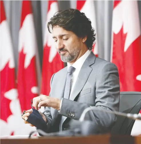  ?? DAVID KAWAI / BLOOMBERG ?? Prime Minister Justin Trudeau takes off a protective mask before a news conference in Ottawa Wednesday. When asked to explain why he didn’t recuse himself from the WE deal he cited his past efforts to serve youth in Canada.