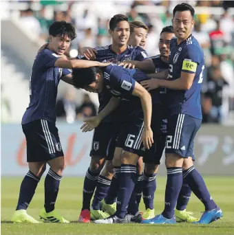  ?? Reuters ?? Japan’s Takehiro Tomiyasu, centre, is congratula­ted by teammates after heading home the winning goal against Saudi Arabia at Sharjah Stadium yesterday