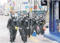  ?? REUTERS ?? South Korean soldiers in protective gear make their way to disinfect buildings in Daegu, South Korea on Saturday.