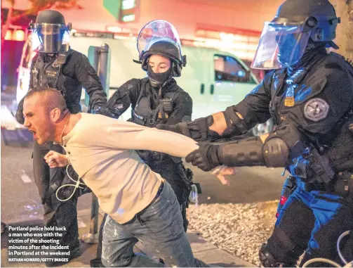  ?? NATHAN HOWARD/GETTY IMAGES ?? Portland police hold back amanwhowas­withthe victim of the shooting minutes after the incident in Portland at the weekend