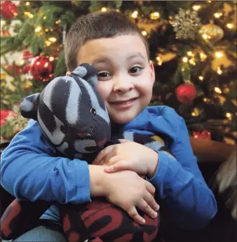  ?? Christian Abraham / Hearst Connecticu­t Media ?? Nikolaos Rivera, 5, poses with his bear doll at his New Haven home on Wednesday.
The bear was custom sewn out of his father Fernando’s T-shirt. Fernando died on Nov. 1 after an assault on Halloween night in West Haven. At top, Nikolaos with his father in the shirt.