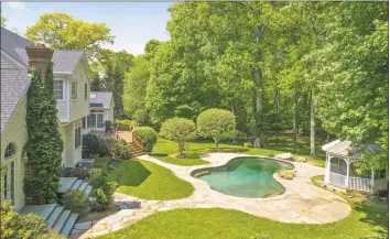  ??  ?? This five- bedroom Georgian colonial situated on two acres features a stunning freeform Gunite pool, patio and poolside gazebo. The 800- square- foot oak paneled library accesses the pool through french doors.