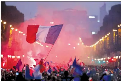  ?? AP/FRANCOIS MORI ?? A man waves the French flag on the Champs-Elysees avenue after France won the World Cup after beating Croatia 4-2 on Sunday in Moscow. The championsh­ip was France’s first since 1998 when it defeated Brazil 3-0.