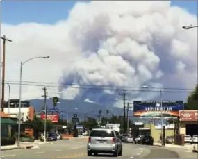  ?? BETH HARRIS — THE ASSOCIATED PRESS ?? Towering columns of smoke rise Monday from two wildfires on the San Gabriel Mountains as viewed from Pasadena.