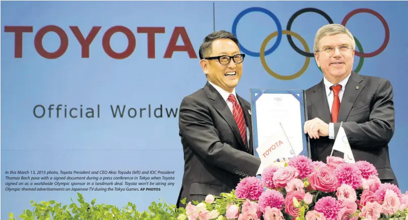  ?? AP PHOTOS ?? In this March 13, 2015 photo, Toyota President and CEO Akio Toyoda (left) and IOC President Thomas Bach pose with a signed document during a press conference in Tokyo when Toyota signed on as a worldwide Olympic sponsor in a landmark deal. Toyota won’t be airing any Olympic-themed advertisem­ents on Japanese TV during the Tokyo Games.