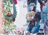  ?? DAVID ZALUBOWSKI/AP ?? Mourners gather outside the door of a tattoo parlor Tuesday in central Denver. Five people were killed and two wounded in a shooting rampage on Monday.