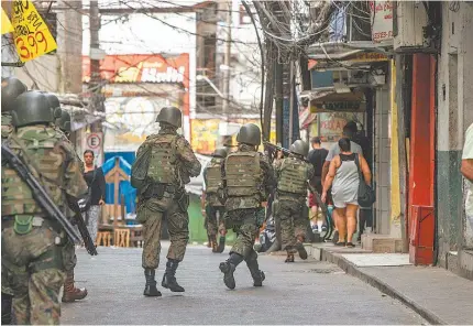  ?? MARCIO MERCANTE/AGENCIA O DIA ?? Soldados chegam à Rocinha para assumir posições em apoio à polícia: operação começou em meio a moradores circulando pela comunidade