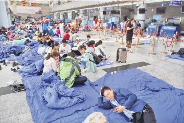  ??  ?? Stranded passengers rest at the departure hall of Jiuzhaigou airport near the remote, mountainou­s area struck by a deadly earthquake in Sichuan province, China. — Reuters photo