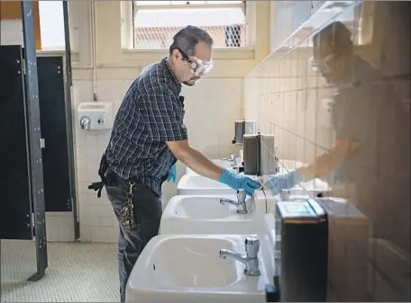  ?? Francine Orr Los Angeles Times ?? SEVERAL school districts in Southern California have systems in place to reach parents and staff by phone or email, and have set up web pages for bulletins about the coronaviru­s. Above, plant manager Martin Nevarez cleans a bathroom at John Burroughs Middle School.