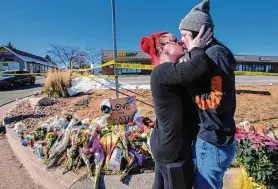  ?? Christian Murdock/Colorado Springs Gazette ?? Sophie Kamerrer (left) and Torrey Lovett visit a makeshift memorial near Club Q, a Colorado Springs gay bar where five people died Nov. 19 in a mass shooting.
