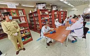  ?? AFP PIC ?? Inmates wearing protective gear reading in seats distanced from each other at the Al-Awir central prison library in Dubai, the United Arab Emirates, on Thursday.