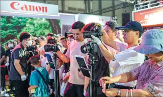  ?? PROVIDED TO CHINA DAILY ?? Visitors gather at the booth of Canon during an expo in Shanghai.