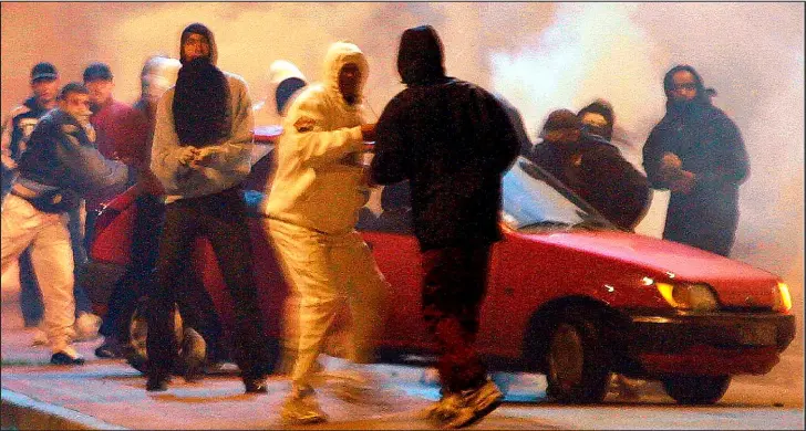  ??  ?? Streets of fire: Against a background of smoke and flame, hooded youths gather to hurl rocks at riot police in Toulouse, another provincial city to be engulfed by violence