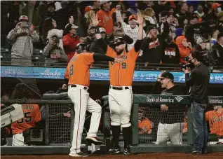  ?? Tony Avelar / Associated Press ?? Brandon Belt (9) celebrates with third-base coach Ron Wotus after a replay showed that Buster Posey was safe at first, giving the Giants a 3-2 victory over the Dodgers on Sept. 3.