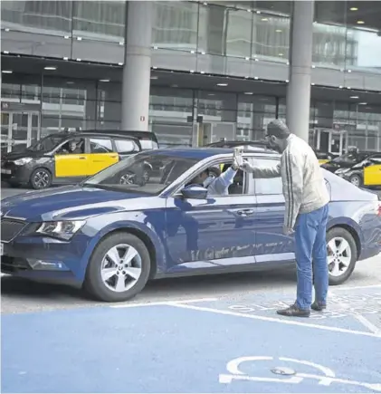  ?? ALBERT BERTRAN ?? Un taxista intenta tomar una fotografía de un conductor de Uber, en el aeropuerto de Barcelona, el 13 de marzo.