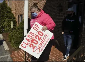  ?? BEN HASTY — MEDIANEWS GROUP ?? Carrie McCarty carries a sign to a customer’s car Wednesday during the distributi­on of the 2020senior signs that she and Denise Benfield are having custom printed and are distributi­ng. In the rear is Shaun Michalski, 16.