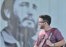  ??  ?? A man with a beard walks near a poster with the image of Cuban late leader Fidel Castro in Havana.