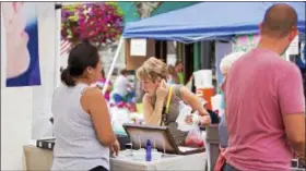  ?? CARRIE GARLAND — THE NEWS-HERALD ?? Gayle Sikula checks out the craft of a vendor at the 2017 Willoughby ArtsFest. The event returns to downtown Willoughby on July 21. For more informatio­n, visit willoughby­artsfest.com.