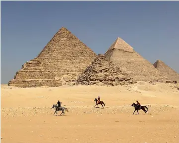  ?? — AFP photo ?? Horse riders gallop near the Giza pyramids, on the southweste­rn outskirts of the Egyptian capital Cairo.