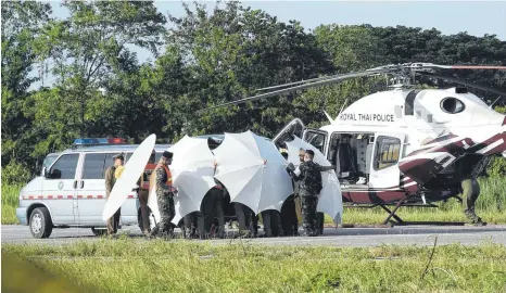  ?? FOTO: AFP ?? Ein Rettungste­am bringt eine Trage, auf der ein geborgenes Kind aus der Höhle im Norden von Thailand liegt, zu einem Helikopter. Polizei und Militär schirmen das Gelände derweil ab.