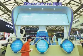  ?? LONG WEI / FOR CHINA DAILY ?? A visitor walks past a Tencent booth at a high-tech exhibition in Shanghai.