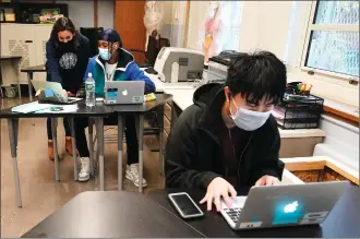  ?? AP File Photo/Kathy Willens ?? In this Oct. 29 file photo, student Tai Nguyen, right, works on his laptop as instructor Chaya Baras, left, helps student Kenny Scottborou­gh, 19, navigate an online lesson at West Brooklyn Community High School in New York. After beginning the year grappling with exasperati­ng delays in their supply chains, the personal computer industry found itself scrambling to keep up with the surging demand for machines that became indispensa­ble during a pandemic that kept millions of workers and students at home.