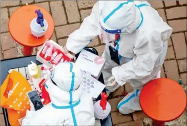  ?? AFP ?? Medical workers prepare to conduct nucleic acid tests for for residents in Jilin on Saturday.