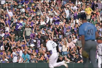  ?? PHOTOS BY HYOUNG CHANG — THE DENVER POST ?? Colorado Rockies fans celebrate first baseman Kris Bryant’s home run during the eighth inning of a their home-opener against the Tampa Bay Rays at Coors Field in Denver.