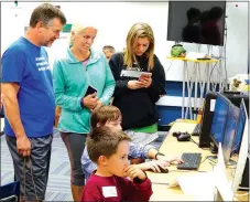  ?? Photo by Randy Moll ?? Henry Curran and Channing Babb worked on the computers in the EAST classroom at Gentry Primary School on Oct. 20 while Danny and Katy Kinser and their daughter, Sidney, looked on.