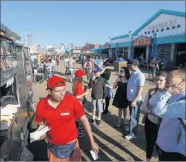  ?? Genaro Molina Los Angeles Times ?? A PERMITTED vendor sells hot dogs on the Santa Monica Pier last month. City permits can be costly, driving many to hawk their wares to beachgoers illegally.