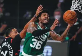  ??  ?? Celtics guard Marcus Smart (right) tries to lay the ball up during their game against the Raptors