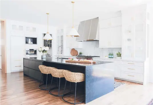  ?? FRESH TWIST STUDIO ?? A kitchen design includes woven Palecek kitchen stools and a striking midnight blue stone island to balance the extensive Shaker-style white and glass cabinetry.