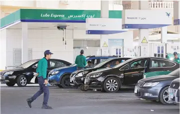  ?? — Reuters photo ?? Workers fill cars as people queue and wait in their cars at Emarat petrol stations after an increase in fuel prices in Cairo, Egypt. Analysts believe the fuel price rises will further increase inflation although it was announced to have decreased in...