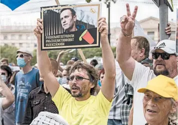  ?? IGOR VOLKOV/AP ?? Alexei Navalny, a top critic of Vladimir Putin, is in a coma in a German hospital. Above, a man supports Navalny.
