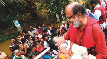  ?? Courtesy: Twitter ?? Thomas Issac carrying a child during the flood in Kuttanad region in Alappuzha. The government expects to complete all reconstruc­tion forced by the flood within two to three years.