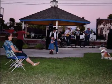  ?? RECORDER PHOTO BY JAMIE A. HUNT ?? Donna Mason sits and enjoys the music, while Sylvia Harrel and a colleague line-dance, with David Eastep and his little granddaugh­ter Davina Miller dance together on stage while Jerry Hall and Trick Shot perform cowboy swing and Western music at The Day of the Cowboy celebratio­n in Centennial Park in Portervill­e, on Saturday.