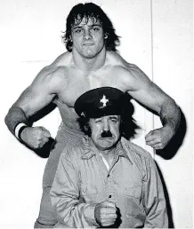  ??  ?? Tom Billington, the Dynamite Kid, in his heyday, flexes his muscle behind manager John Foley. Billington died Wednesday at age 60.