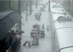  ?? — RAJESH JADHAV ?? People try to cross flooded railway tracks near Sion station in Mumbai on Tuesday.